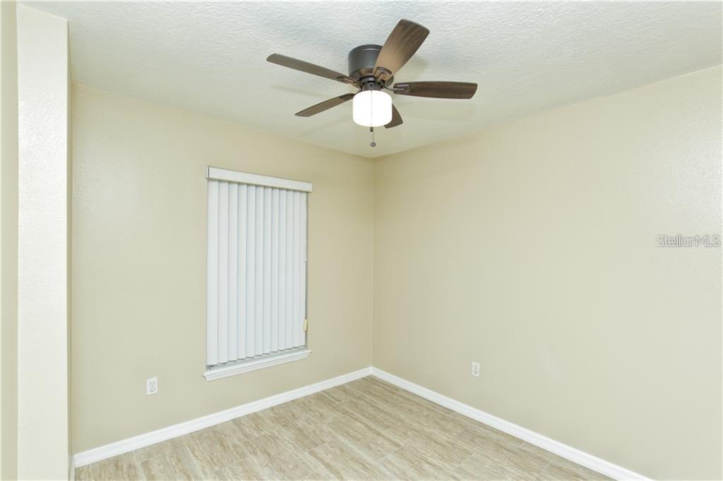 An empty room features light-colored walls, wood-look tile flooring, a window with blinds, and a ceiling fan — 8829 GRAND PALMS CIRCLE UNIT A, KISSIMMEE, FL