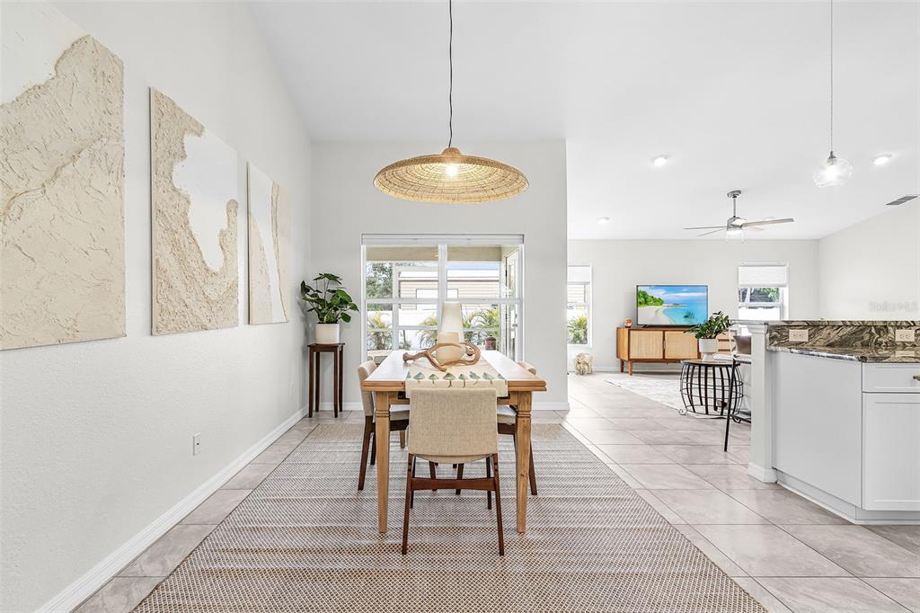 A dining area with a wooden table, woven pendant light, and textured wall art — 10317 WILLIG AVENUE, ENGLEWOOD, FL