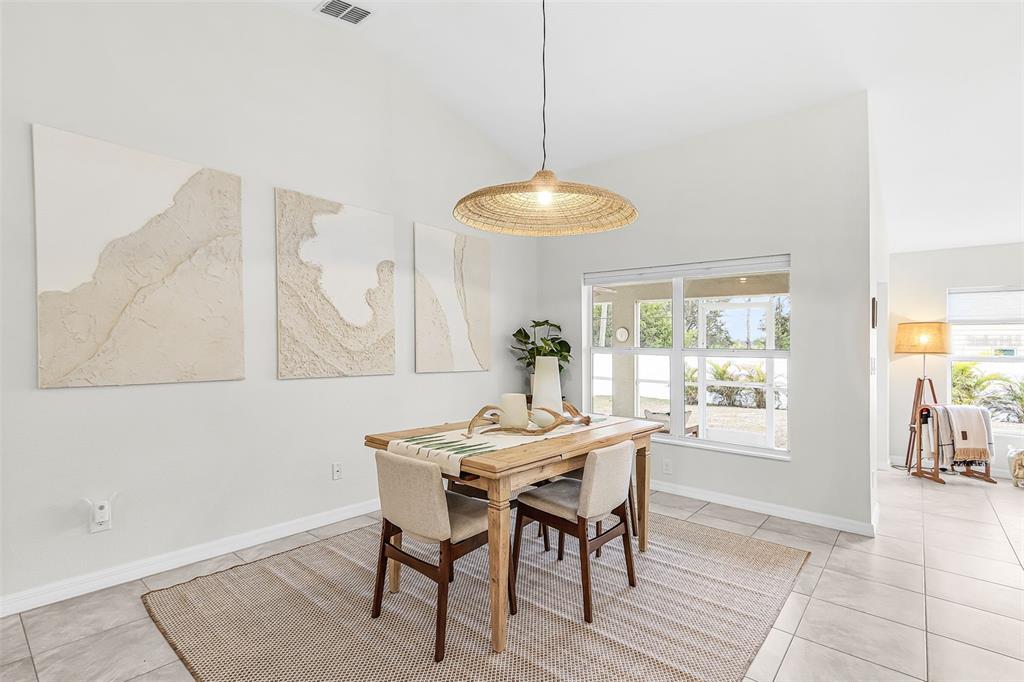 A dining area features a wooden table, textured wall art, and a woven pendant light — 10317 WILLIG AVENUE, ENGLEWOOD, FL