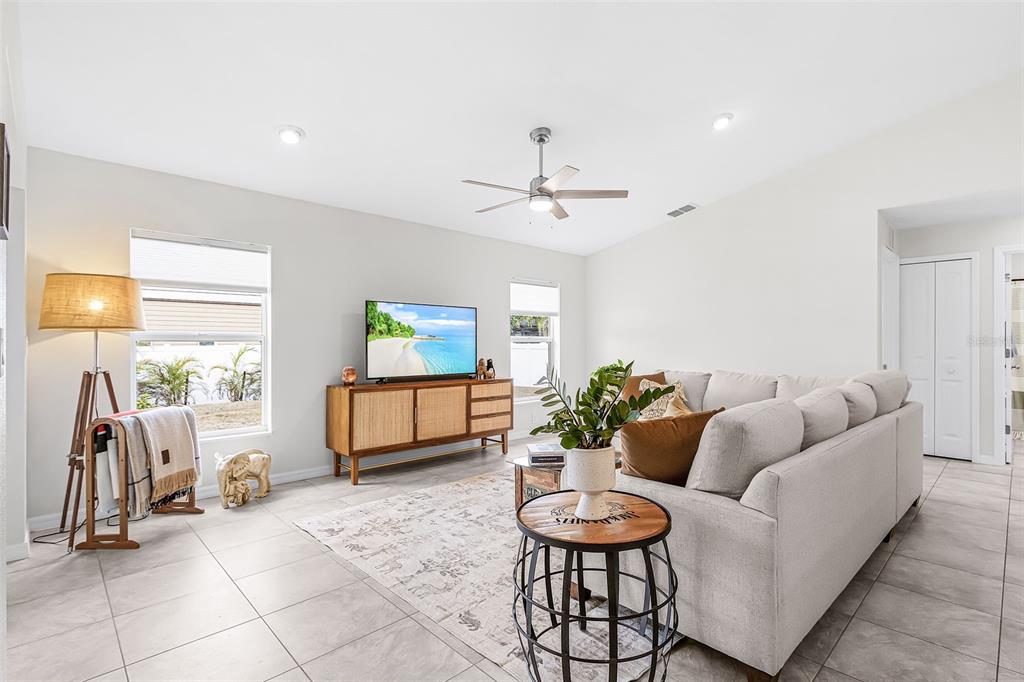 A living room features light tile floors, a gray sectional sofa, and a wood media console — 10317 WILLIG AVENUE, ENGLEWOOD, FL