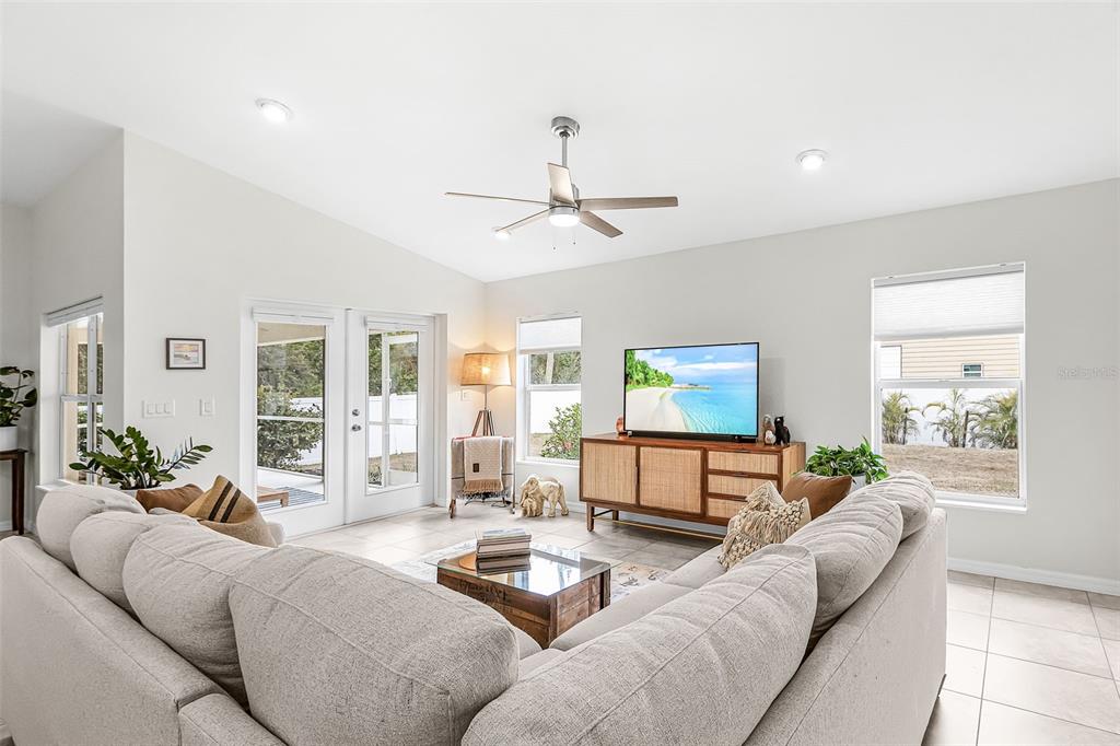 A living room features a sectional sofa, a television on a wooden console, and tile flooring — 10317 WILLIG AVENUE, ENGLEWOOD, FL