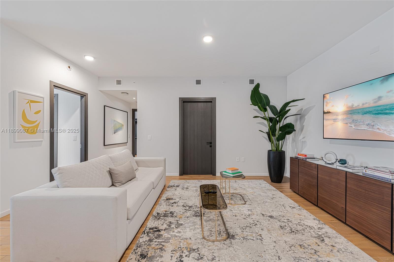 A modern living room features a white sofa, a patterned area rug, and a television — 398 NE 5th St # 3017, Miami FL 33132, MIAMI, FL