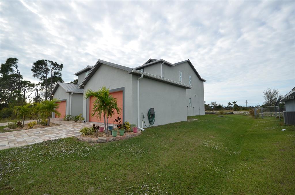 A two-story house with gray stucco siding, orange garage doors, and a paved driveway — 8581 AGATE STREET, PORT CHARLOTTE, FL