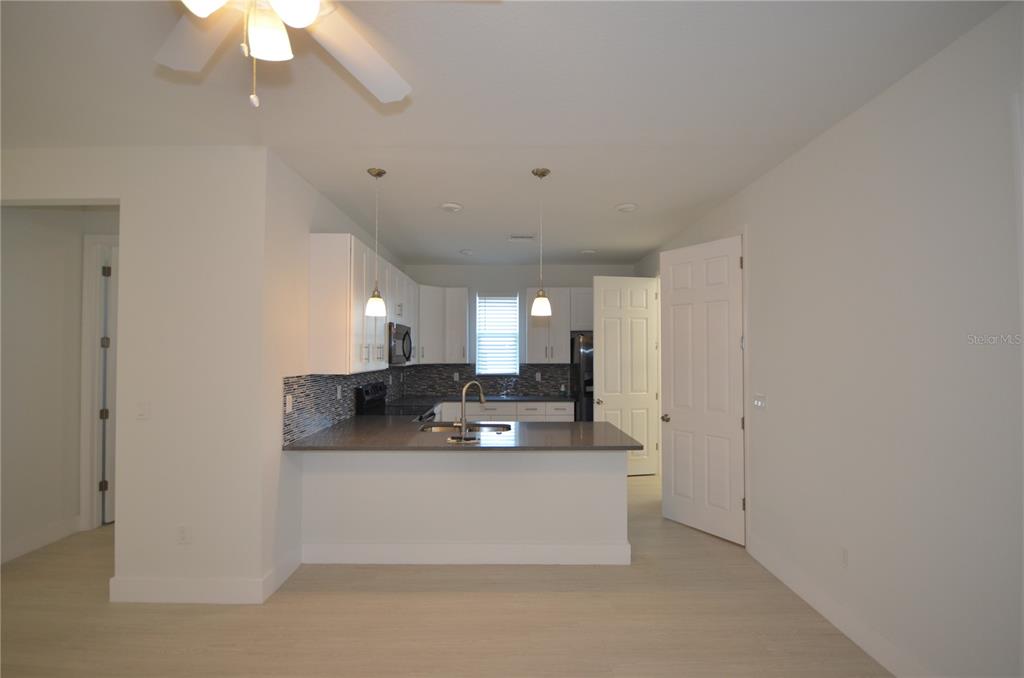 A kitchen features white cabinets, a gray countertop, a tiled backsplash, and two pendant lights — 8581 AGATE STREET, PORT CHARLOTTE, FL