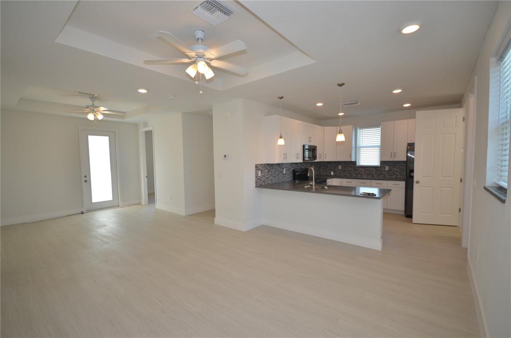 An open-concept kitchen and living area featuring white cabinets, gray countertops, and light flooring — 8581 AGATE STREET, PORT CHARLOTTE, FL