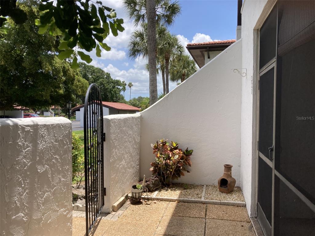 A small outdoor patio features a metal gate, a white privacy wall, and potted plants — 331 BARCELONA DRIVE UNIT 331, BRADENTON, FL