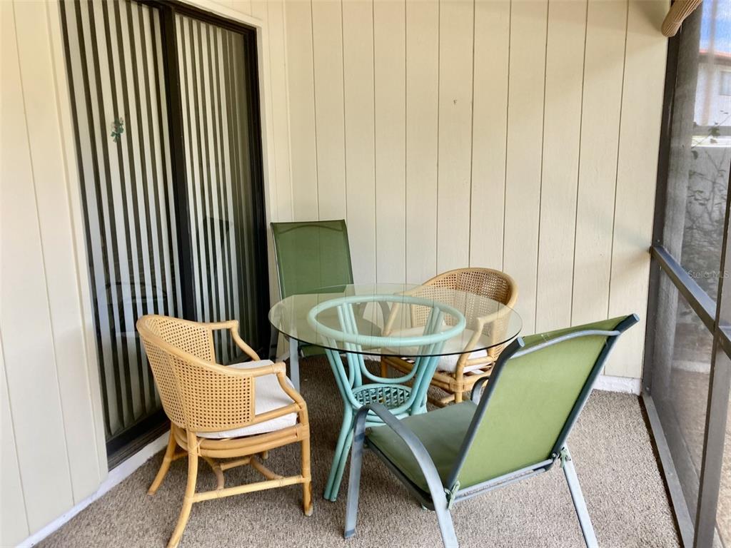 A glass-topped table with four mismatched chairs sits on a screened-in patio — 331 BARCELONA DRIVE UNIT 331, BRADENTON, FL