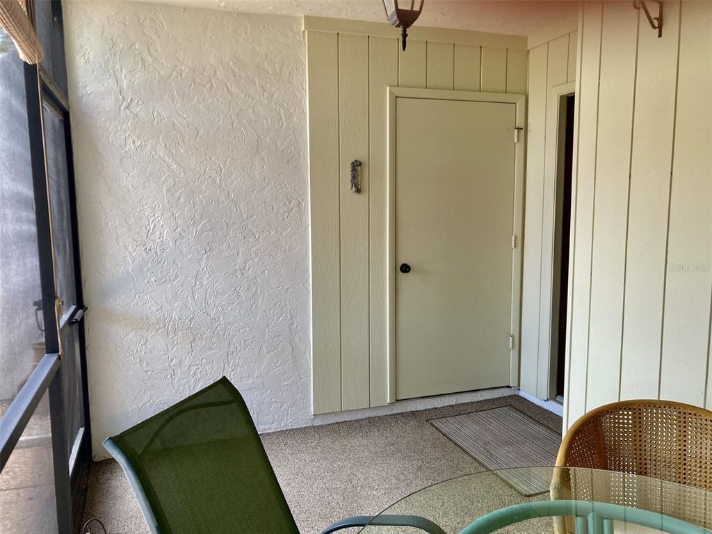A screened-in porch features a textured white wall, light-colored vertical siding, and a door — 331 BARCELONA DRIVE UNIT 331, BRADENTON, FL