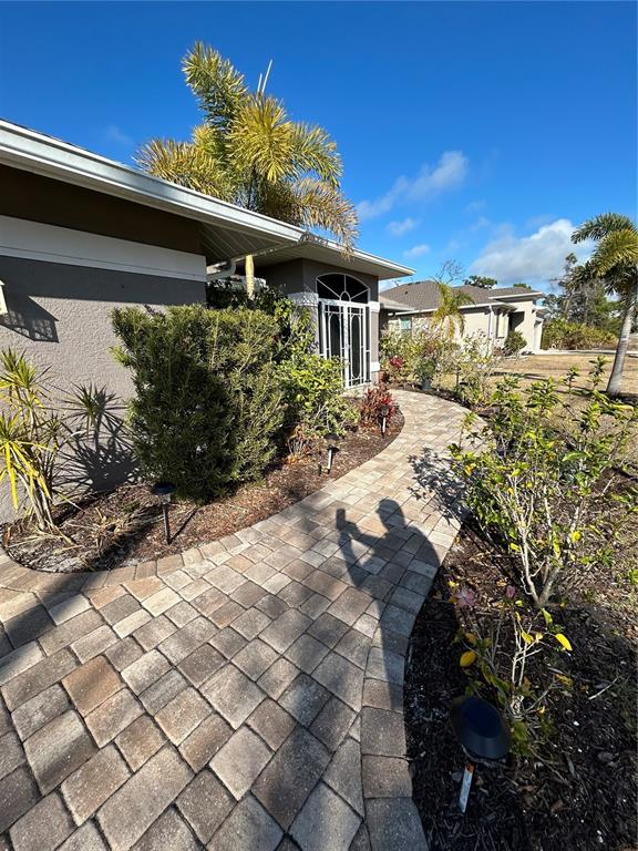 A paved walkway leads to the entrance of a house surrounded by landscaping and palms — 108 BERYL DRIVE, ROTONDA WEST, FL