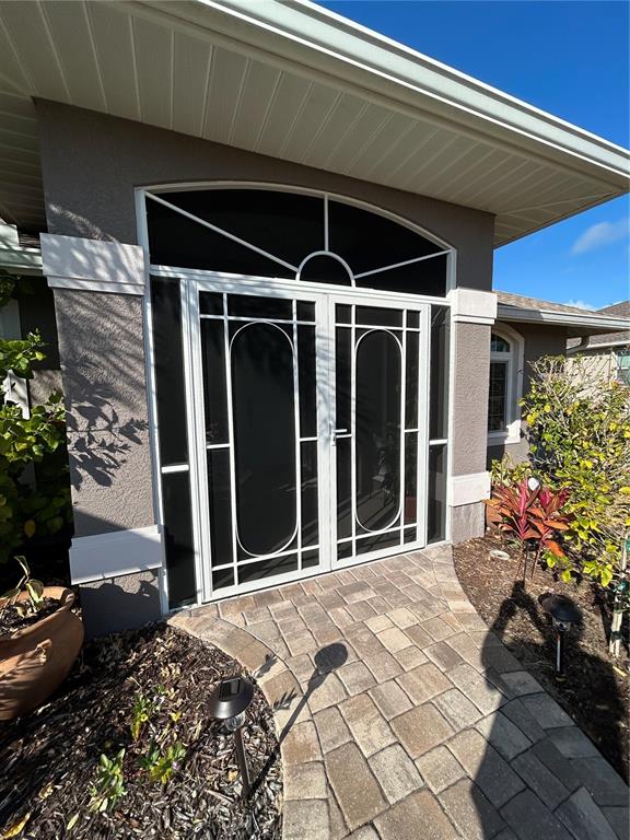 A white double screen door with an arched transom leads to a paved entryway — 108 BERYL DRIVE, ROTONDA WEST, FL