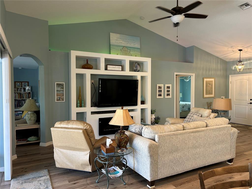 A living room features a white built-in entertainment center, vaulted ceilings, and light blue walls — 108 BERYL DRIVE, ROTONDA WEST, FL
