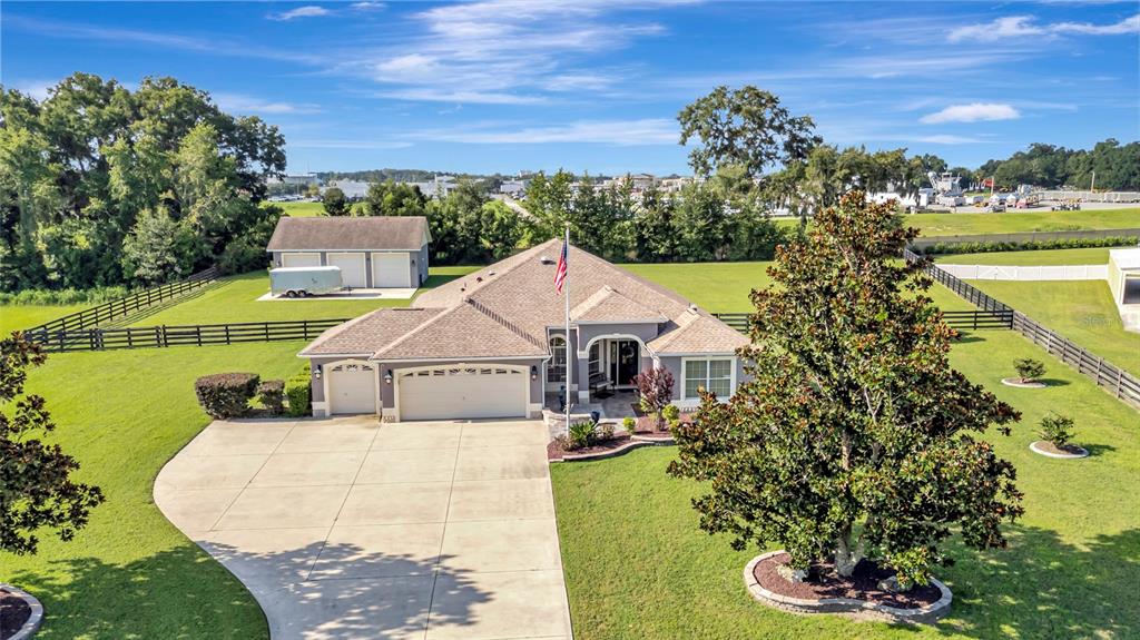 An aerial view of a single-story house with a large driveway, garage, and detached building — 4190 COUNTY ROAD 121D, WILDWOOD, FL