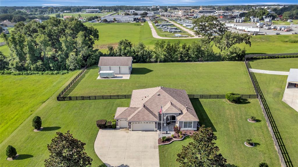 An aerial view shows a house with a detached garage on a large grassy lot — 4190 COUNTY ROAD 121D, WILDWOOD, FL