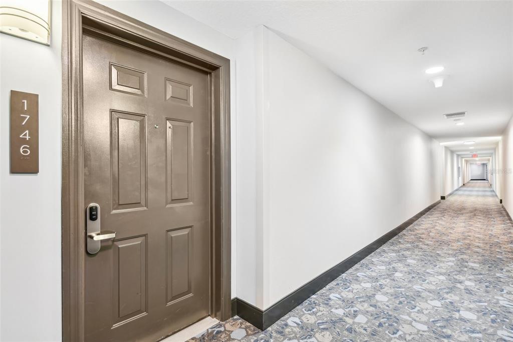A brown door labeled 1746 sits at the end of a long, carpeted apartment hallway — 14501 GROVE RESORT AVENUE UNIT 1746, WINTER GARDEN, FL