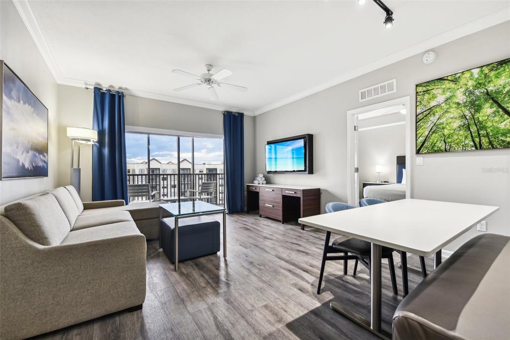 A living room with a sofa, dining table, television, and a balcony with outdoor seating — 14501 GROVE RESORT AVENUE UNIT 1746, WINTER GARDEN, FL
