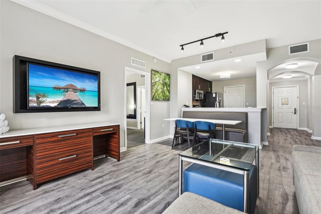 A living room features a wall-mounted television, a dining nook, and wood-look flooring — 14501 GROVE RESORT AVENUE UNIT 1746, WINTER GARDEN, FL