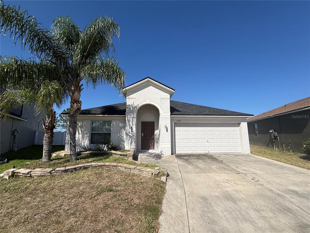 A single-story house with a palm tree, stone landscaping, and a two-car garage — 2370 DOVESONG TRACE DRIVE, RUSKIN, FL
