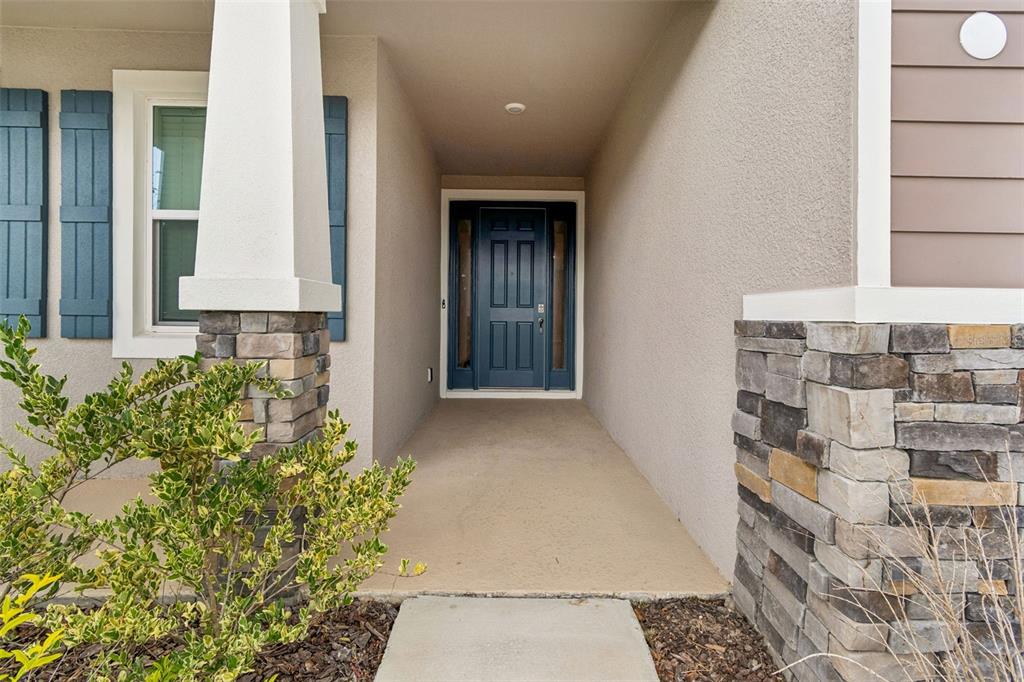 A covered entryway features a blue front door, stone pillars, and blue shutters on the window — 10959 COTTON VALE PLACE, SAN ANTONIO, FL