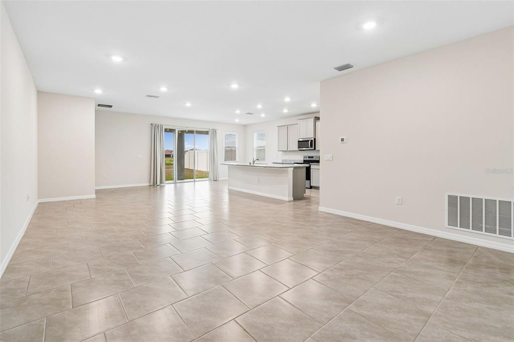 An open-concept kitchen and living area features light tile flooring and a central island — 10959 COTTON VALE PLACE, SAN ANTONIO, FL