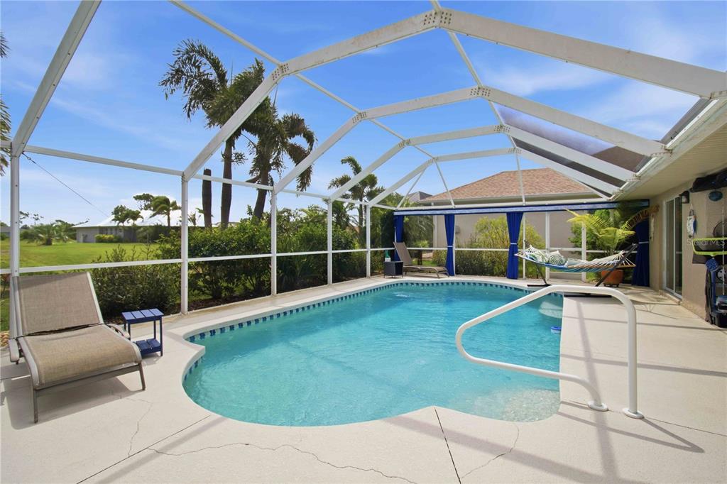 A screened-in swimming pool with a lounge chair and hammock on a concrete patio — 242 WHITE MARSH LANE, ROTONDA WEST, FL