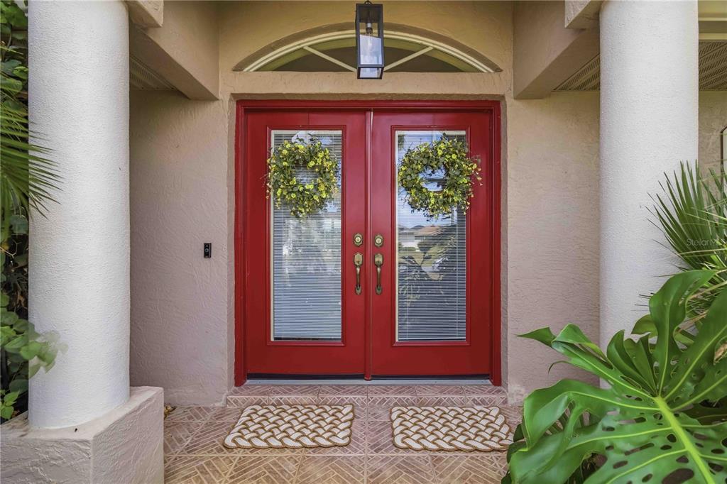A red double front door with wreaths and glass inserts sits between two white columns — 242 WHITE MARSH LANE, ROTONDA WEST, FL
