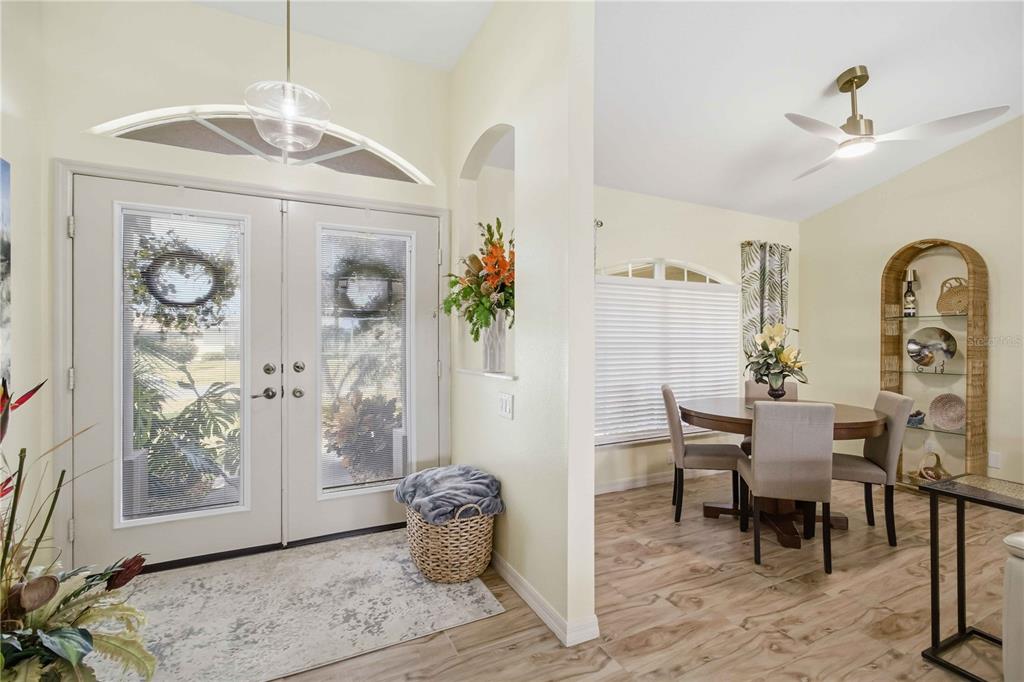 An entryway with double glass doors leads into a dining area with wood-look flooring — 242 WHITE MARSH LANE, ROTONDA WEST, FL
