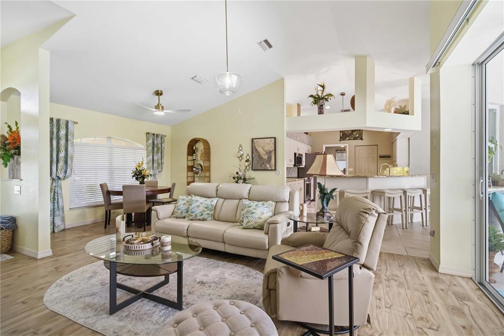 A living room with light-colored walls, tile flooring, a beige sofa, and an open kitchen — 242 WHITE MARSH LANE, ROTONDA WEST, FL
