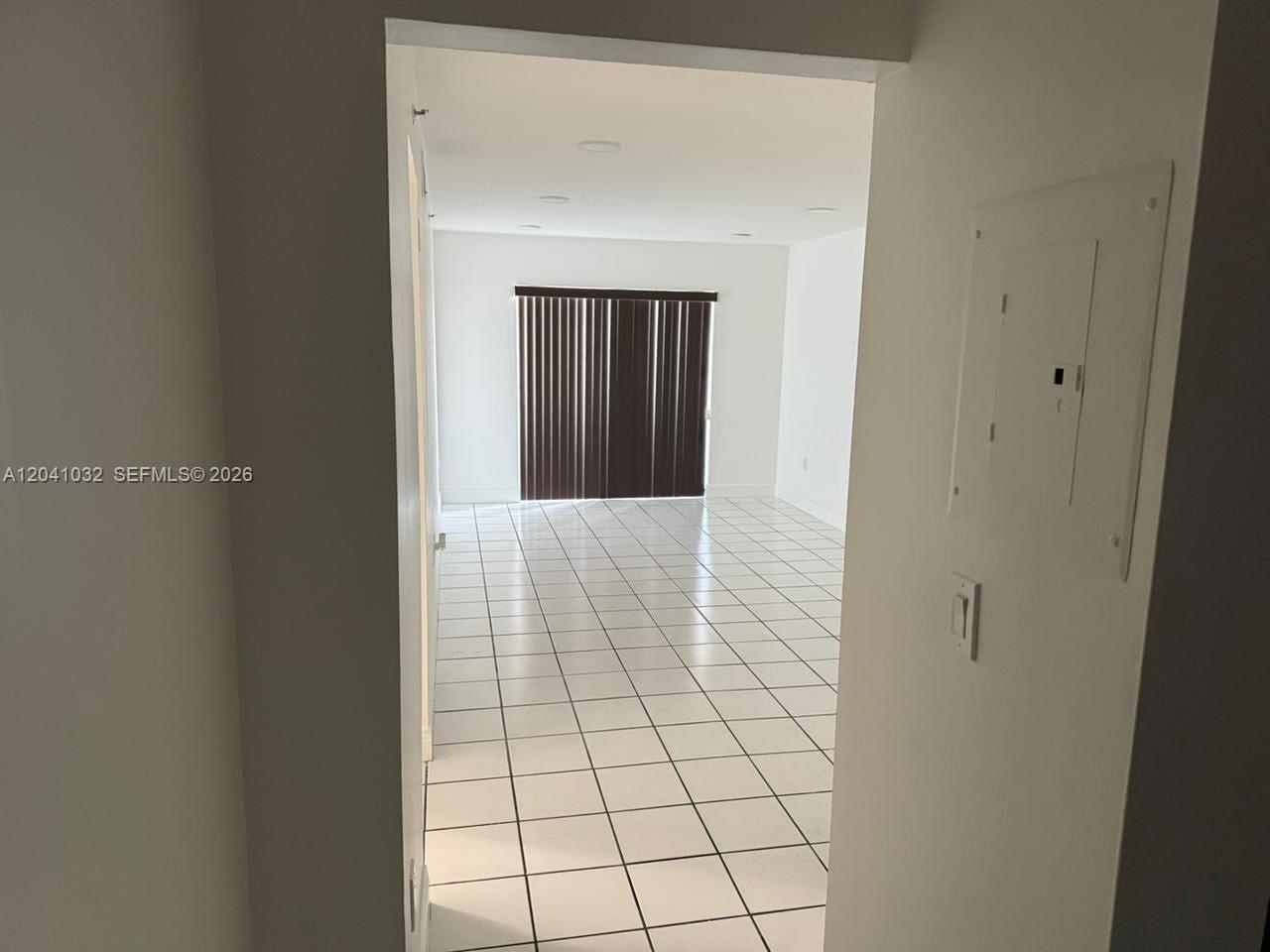 An interior view shows a room with white tiled floors and a large window with blinds — 600 NW 32nd Pl # 303, Miami FL 33125, MIAMI, FL