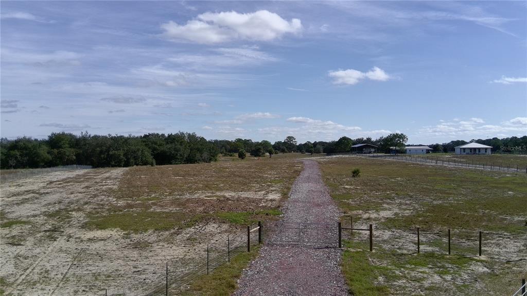 A wire fence stands in the foreground of a grassy field with trees and clouds — 4547 GLENN SAINT MARY ROAD, LAKE WALES, FL