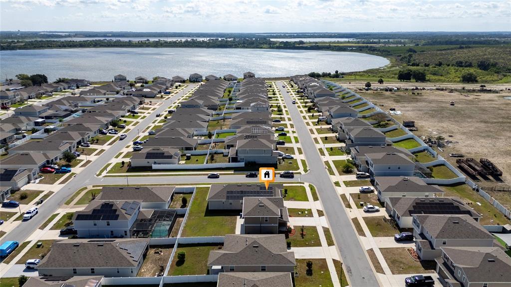 An aerial view shows a suburban neighborhood of houses with solar panels near a lake — 339 LAKE SMART CIRCLE, WINTER HAVEN, FL