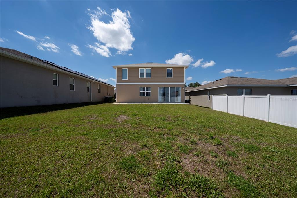 The backyard of a two-story house features a concrete patio and a white vinyl fence — 339 LAKE SMART CIRCLE, WINTER HAVEN, FL
