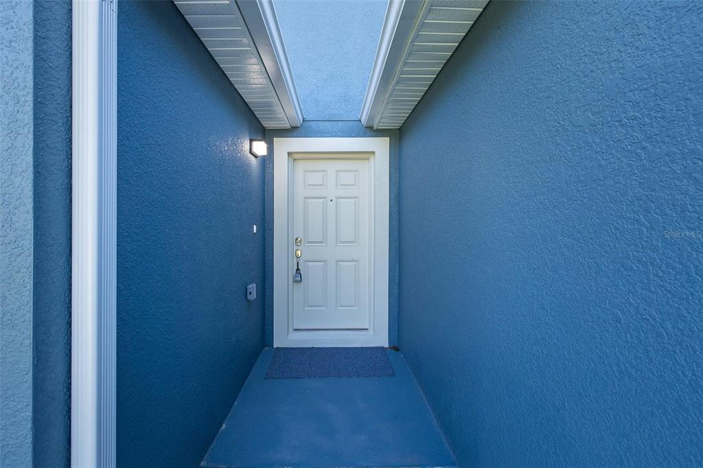 A white front door is centered within a recessed entryway featuring blue exterior walls — 5422 CHARLES STREET, NEW PORT RICHEY, FL
