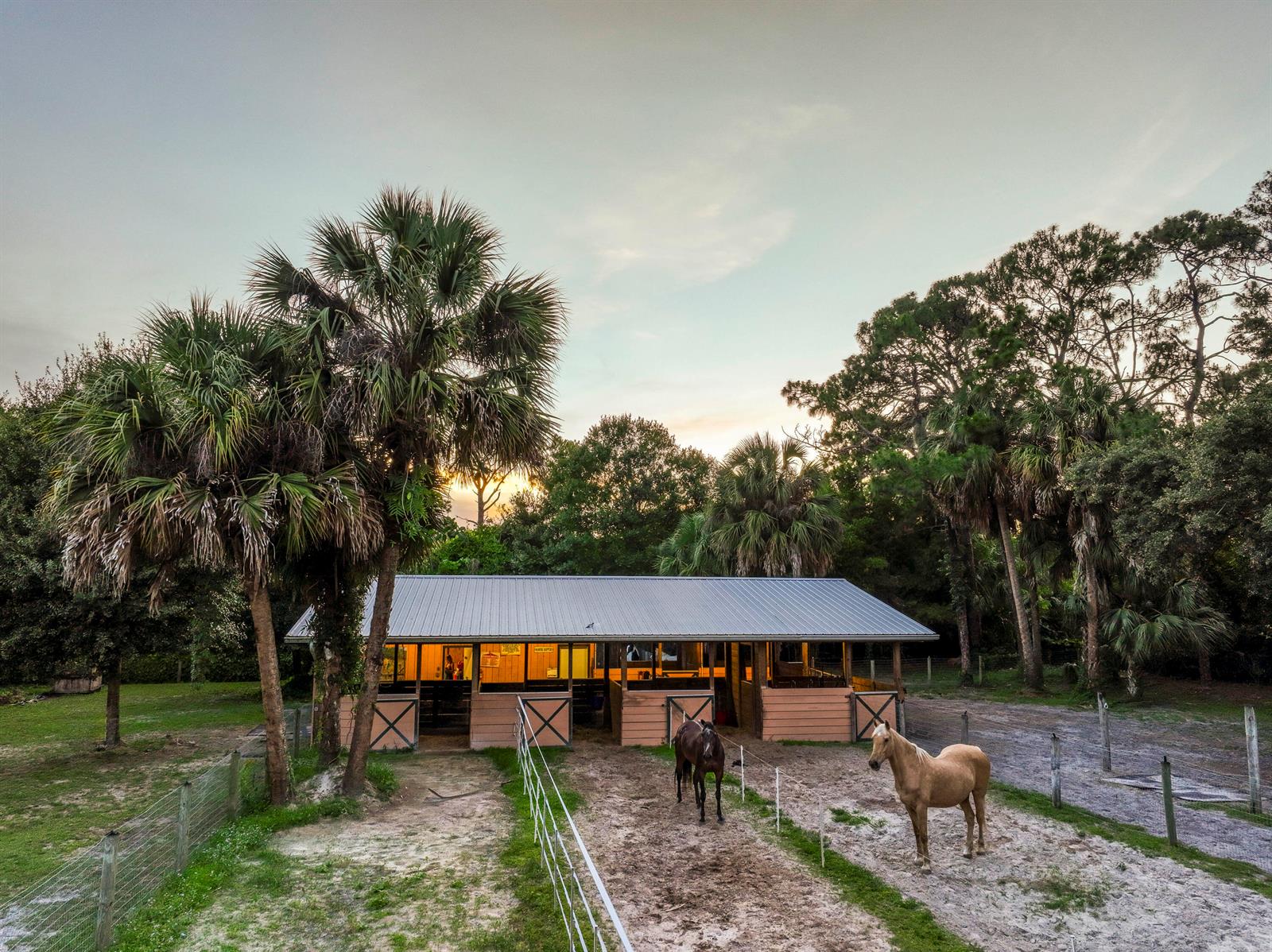 An exterior view of a horse stable with two horses standing in a dirt paddock — 11065 164th Court N, Jupiter FL 33478, JUPITER, FL