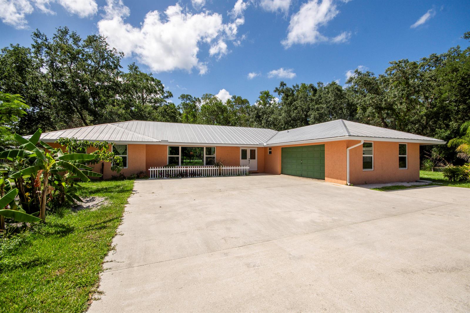 A single-story peach-colored house with a metal roof, green garage door, and concrete driveway — 11065 164th Court N, Jupiter FL 33478, JUPITER, FL