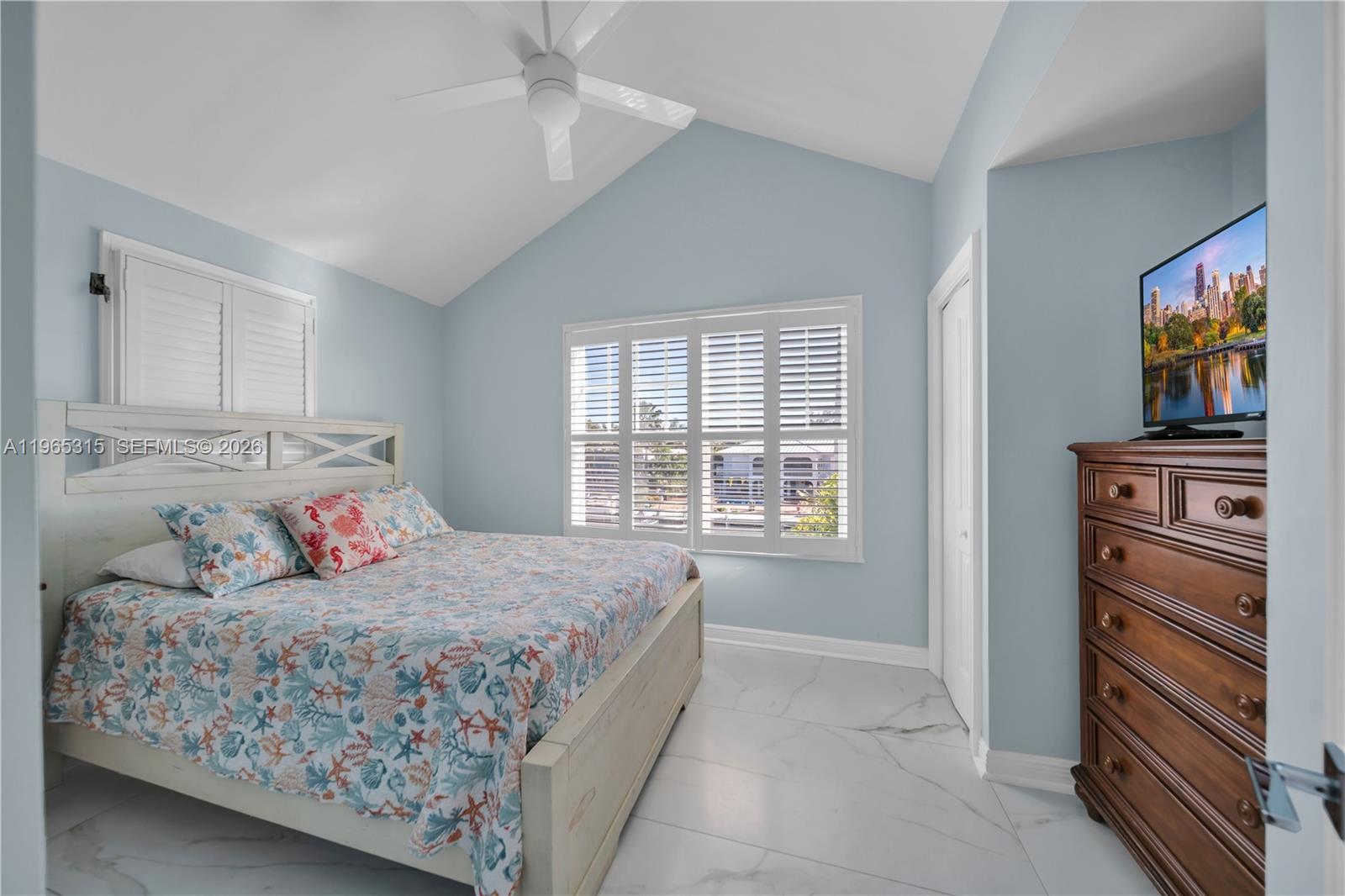 A bedroom with light blue walls, a vaulted ceiling, a bed, and a wooden dresser — 7026 Harbor Village Dr, Duck FL 33050, DUCK, FL