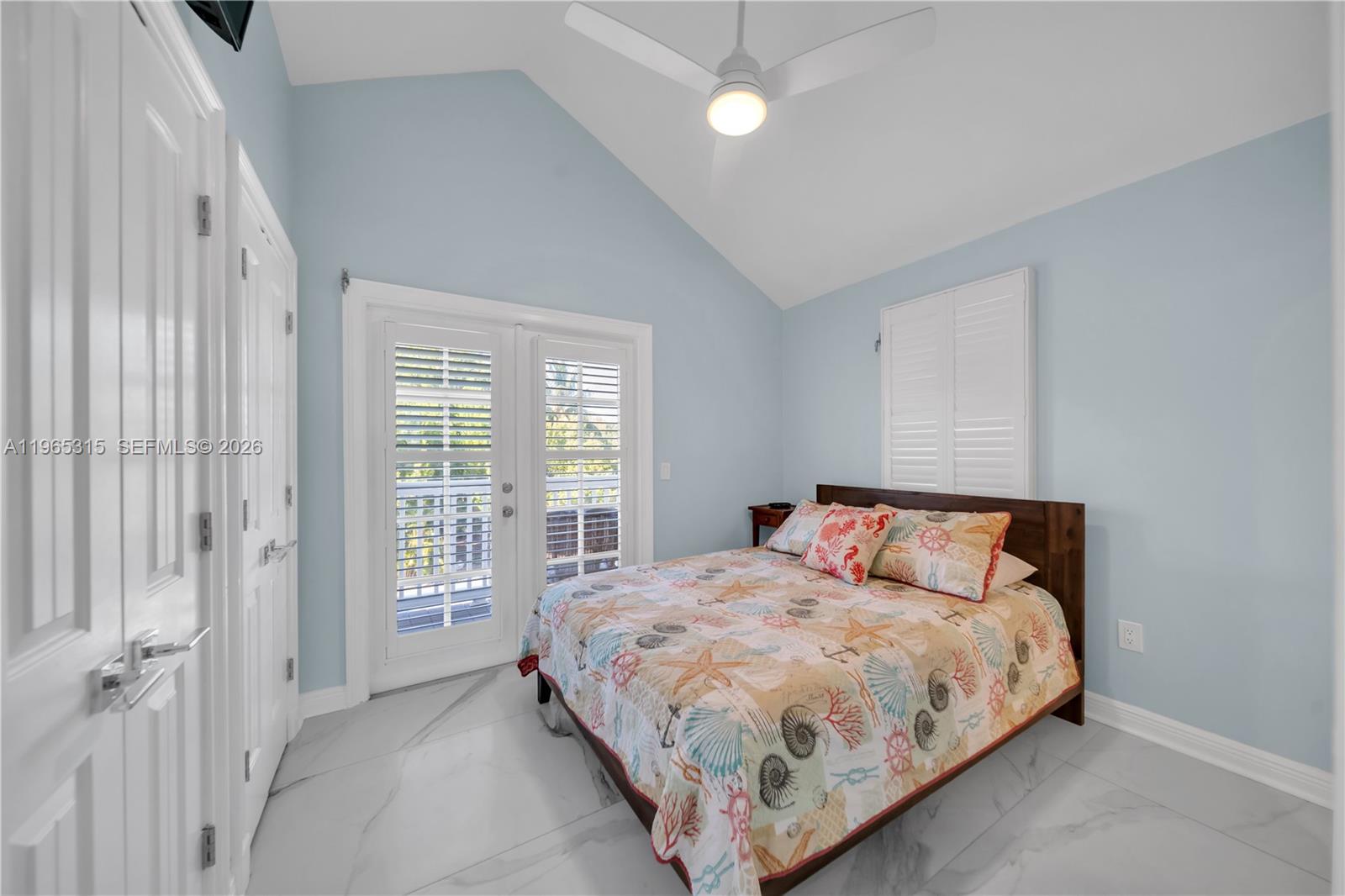 A bedroom features light blue walls, a vaulted ceiling, marble floors, and a queen bed — 7026 Harbor Village Dr, Duck FL 33050, DUCK, FL