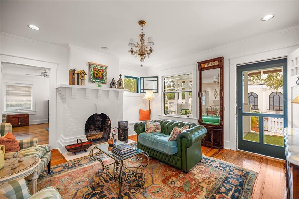 A living room features a white brick fireplace, a green leather sofa, and hardwood floors — 458 SCOTLAND STREET, DUNEDIN, FL