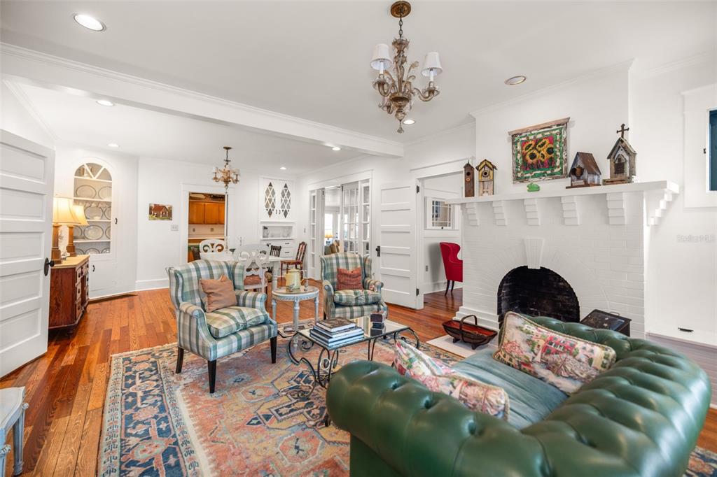 A living room features a white brick fireplace, a green tufted sofa, and hardwood floors — 458 SCOTLAND STREET, DUNEDIN, FL