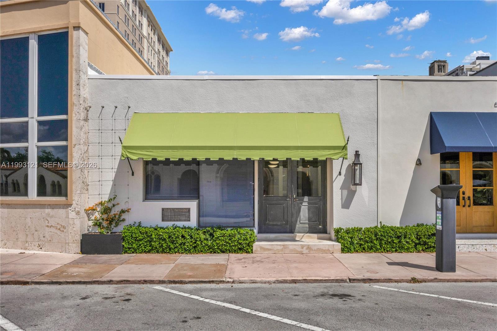 The exterior of a commercial building features a green awning, dark double doors, and landscaping — 337 Palermo Ave, Coral Gables FL 33134, CORAL GABLES, FL