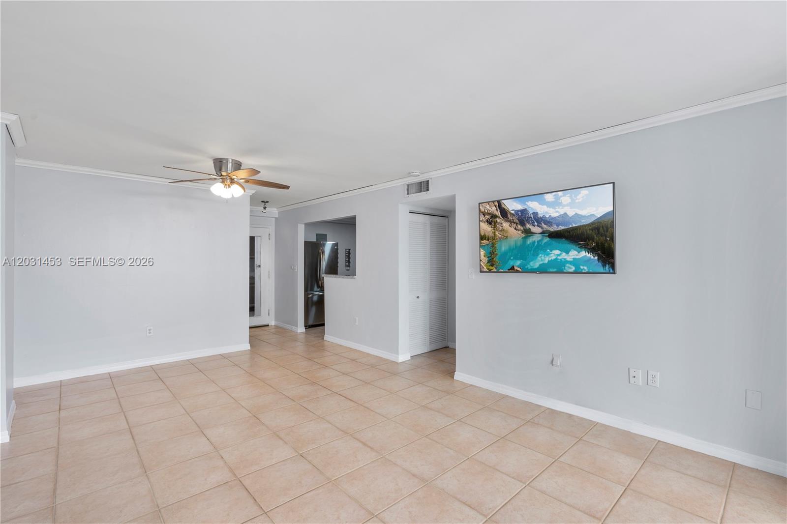 A living room features light gray walls, beige tile flooring, and a wall-mounted television — 1605 Bay Rd # 503, Miami Beach FL 33139, MIAMI BEACH, FL