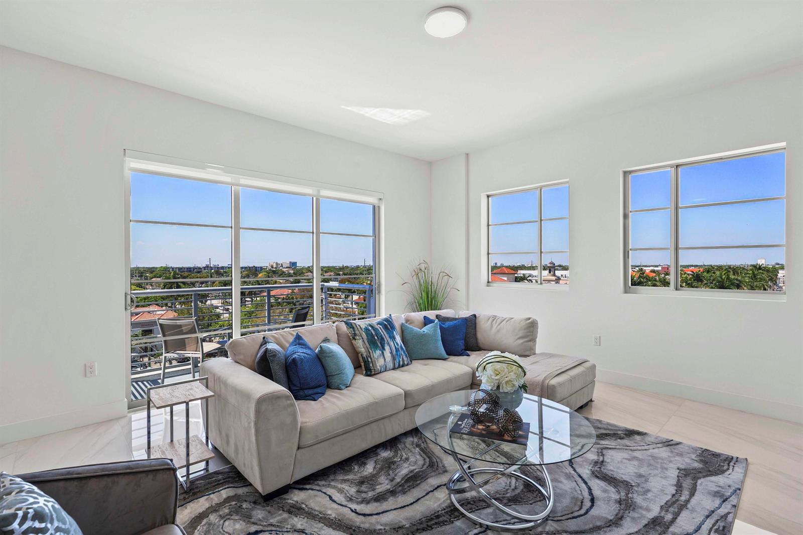 A bright living room features a beige sectional sofa, a glass coffee table, and large windows — 155 E Boca Raton Road # 723, Boca Raton FL 33432, BOCA RATON, FL