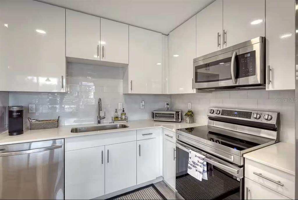 A modern kitchen featuring white cabinets, stainless steel appliances, and a light-colored countertop — 1709 N TAMIAMI TRAIL UNIT 220, SARASOTA, FL