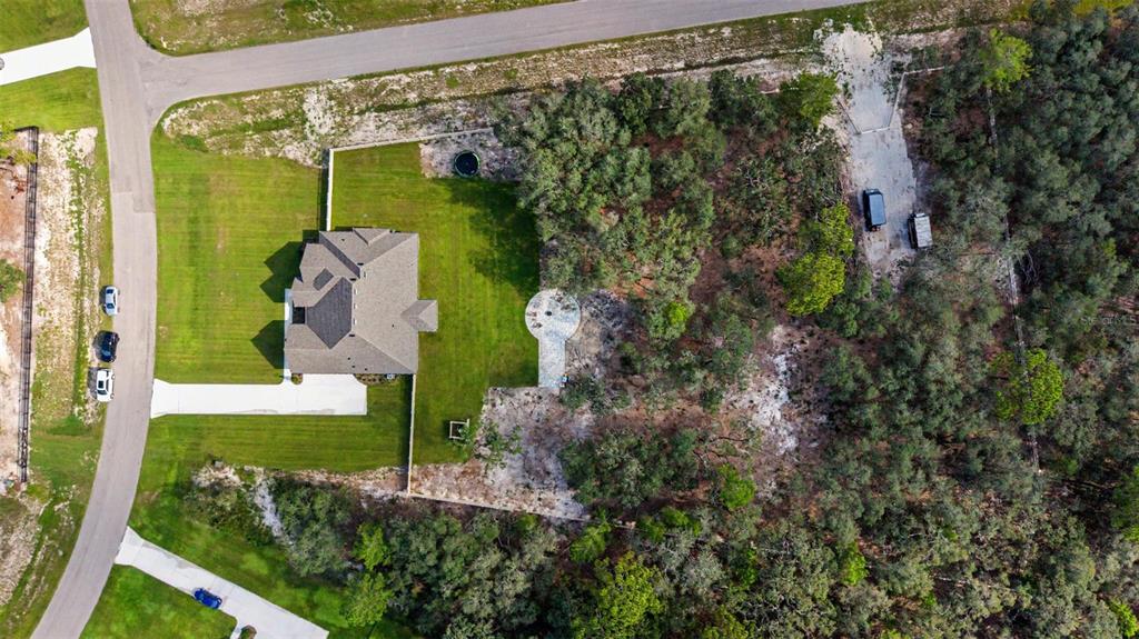 An aerial view shows a house with a large lawn, circular patio, and wooded backyard — 17422 NOKOTA AVENUE, HUDSON, FL
