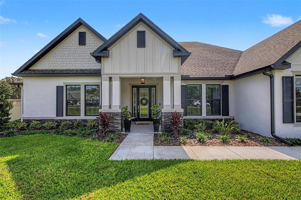 A modern single-story house with a white stucco exterior, stone accents, and a covered entryway — 17422 NOKOTA AVENUE, HUDSON, FL