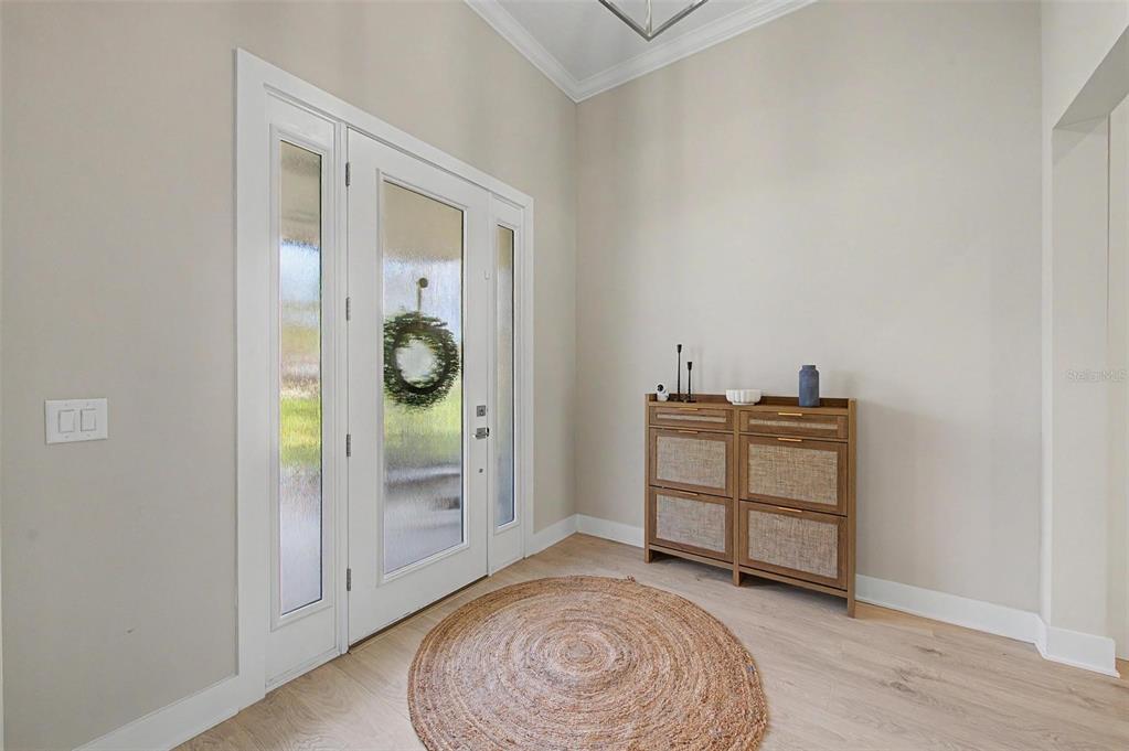 An entryway features light wood flooring, a round jute rug, and a wooden storage cabinet — 17422 NOKOTA AVENUE, HUDSON, FL