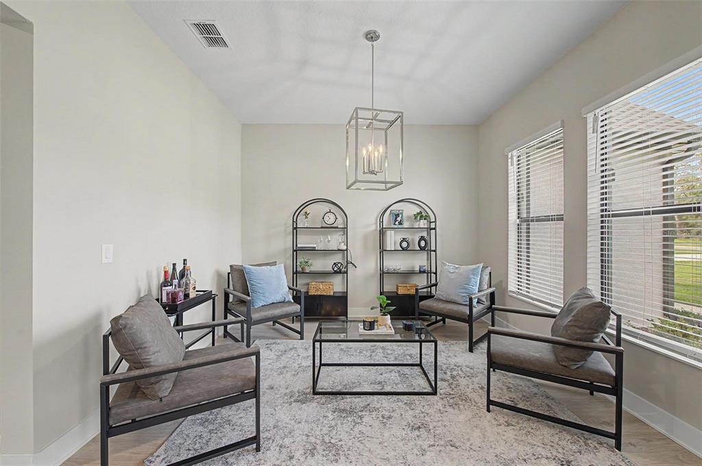 A living room features four gray armchairs, a glass coffee table, and two arched metal shelves — 17422 NOKOTA AVENUE, HUDSON, FL