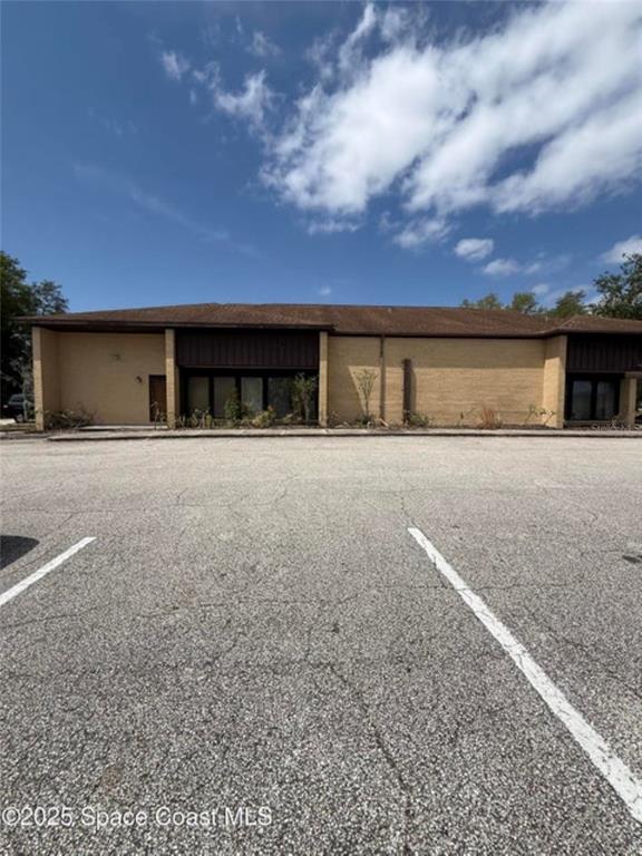 A single-story commercial building with a brick facade and a large asphalt parking lot — 1855 JESS PARRISH COURT, TITUSVILLE, FL