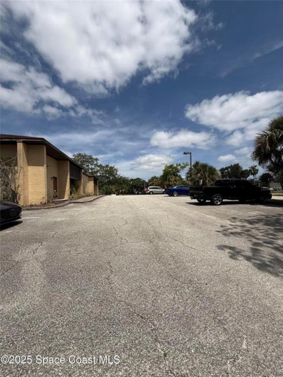 An asphalt parking lot sits in front of a tan building under a cloudy sky — 1855 JESS PARRISH COURT, TITUSVILLE, FL