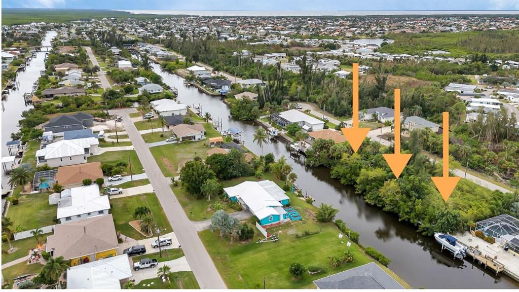 An aerial view shows a residential canal neighborhood with three orange arrows pointing toward trees — 3410, 3402, 3420 COLONY COURT, PUNTA GORDA, FL