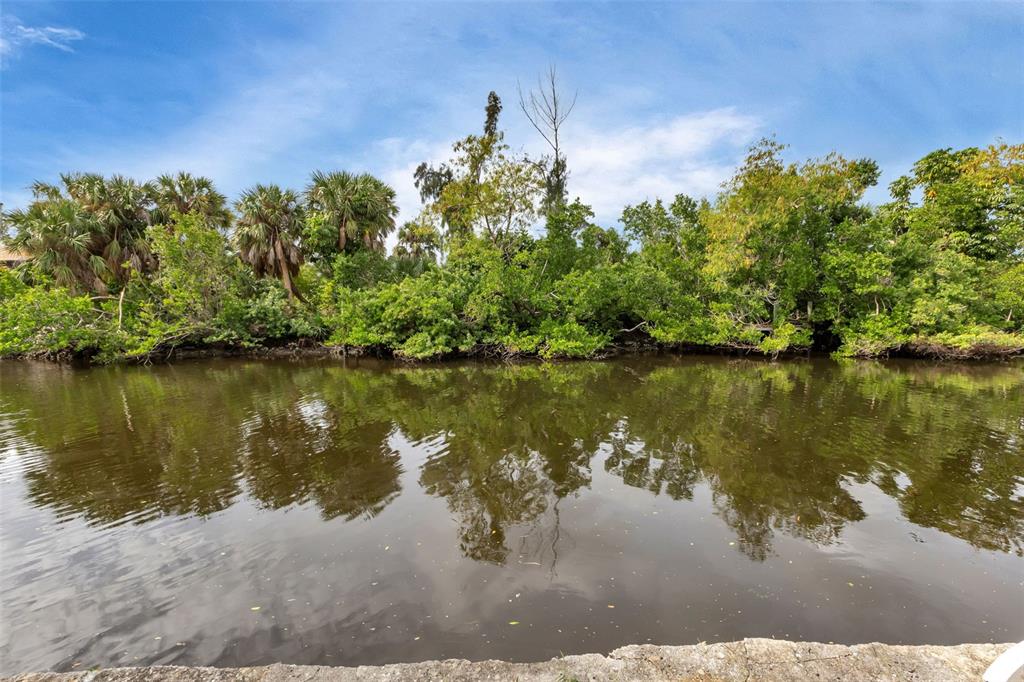 A view of a calm canal bordered by lush green trees and palm trees — 3410, 3402, 3420 COLONY COURT, PUNTA GORDA, FL